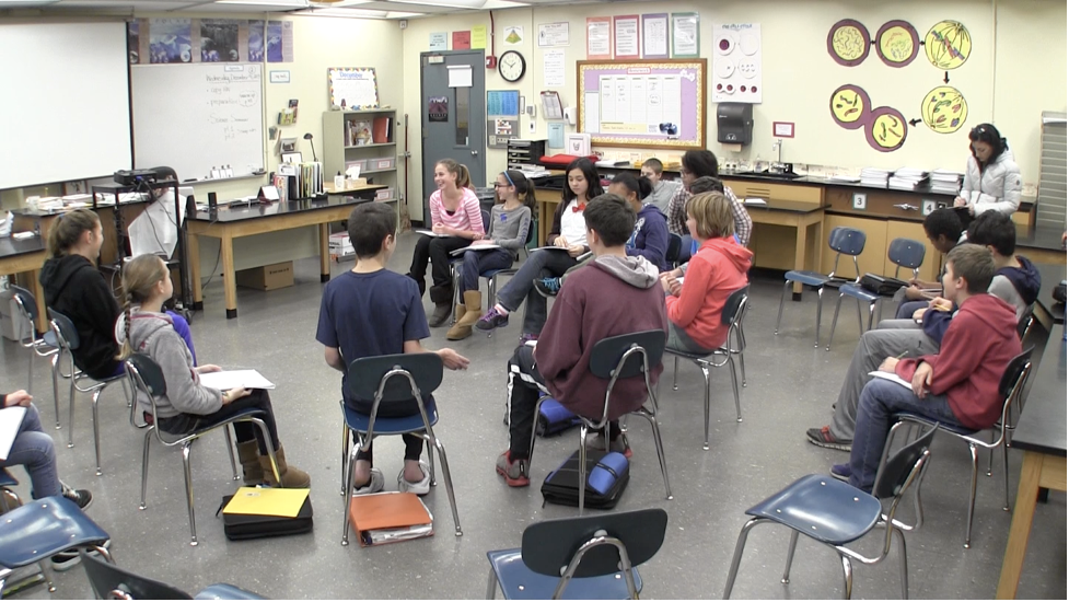 Students in a classroom are seated in a circle